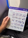 Malmo, Sweden - August 22, 2022: Male traveler on WizzAir airplane flight reading safety brochure before taking off Royalty Free Stock Photo