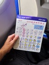 Malmo, Sweden - August 22, 2022: Male traveler on WizzAir airplane flight reading safety brochure before taking off