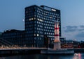 MalmÃÂ¶, Sweden - August 7, 2019: An old lighthouse still stands next to a bridge and the modern hotel building Studio in the