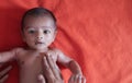 Malnourished baby looking at the camera lying on orange red velvet cloth background. protein energy malnutrition concept Royalty Free Stock Photo