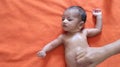 Malnourished baby looking at the camera lying on orange red velvet cloth background. protein energy malnutrition concept Royalty Free Stock Photo