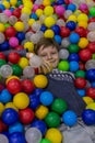 A boy lies among multi-colored plastic balls in a playroom. Happy Birthday party. Royalty Free Stock Photo