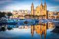 Malta, big church at sunset in front of a port with reflection