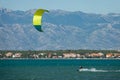 Man on active vacation in Croatia kitesurfs past a coast under the Velebit.