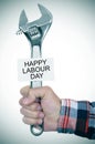 Man with adjustable wrench and signboard with text happy labour