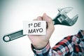 Man with adjustable wrench and signboard with text 1o de mayo, m