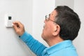 Man adjusting thermostat at home, focus on thermostat. Celsius temperature scale. Royalty Free Stock Photo