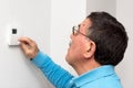 Man adjusting thermostat at home, focus on face. Celsius temperature scale. Royalty Free Stock Photo