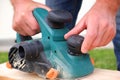 A man adjusts the depth of planing with an electric plane. Close-up on hands with an electric plane. Working with a power tool