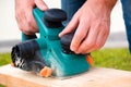 A man adjusts the depth of planing with an electric plane. Close-up on hands with an electric plane. Working with a power tool