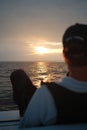 Man admiring a stunning sunset over the serene ocean, with the horizon illuminated by the sunset Royalty Free Stock Photo