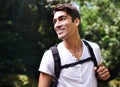 Man, adventure and backpack for hiking in rainforest with smile for thinking, holiday and outdoor in summer. Person Royalty Free Stock Photo