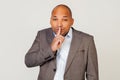 Man african american businessman in a jacket makes a gesture with his hand holding a finger on his lips, asks for Royalty Free Stock Photo