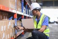 Man African American professional worker wearing safety uniform and hard hat using laptop and scanning box inspect product on