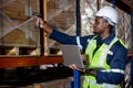 Man African American professional worker wearing safety uniform and hard hat using laptop and scanning box inspect product on