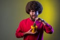 Man with Afro hairstyle holding yellow flower pot with prickly cactus flower, touching prickly plant Royalty Free Stock Photo