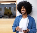 Man with afro standing outside with mobile phone ad coffee Royalty Free Stock Photo