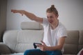 Man aged 20-25 spends his free time playing video games and e-games on a special game console and gesturing into space. Blond man Royalty Free Stock Photo