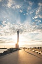 Man aged 25-29 in a yellow jacket walks towards a red-orange lighthouse at sunset. Illuminated by orange light Royalty Free Stock Photo