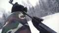 A man aiming a pellet gun towards a target, practicing his aim in the winter. Clip. The shooter in camouflage targets a Royalty Free Stock Photo