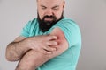 Man with allergy symptoms scratching arm on grey background Royalty Free Stock Photo