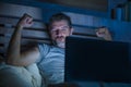 Man alone in bed playing cybersex using laptop computer watching sex movie late at night with lascivious pervert face Royalty Free Stock Photo