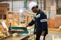 Man American African wearing safety uniform and hard hat working on wood cutting electric machines at workshop manufacturing Royalty Free Stock Photo