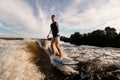 man with an amputated hand is surfing on surfboard trails behind boat. Wakesurfing