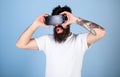 Man with amused look and open mouth enjoying 3D experience. Bearded man with tattoo watching 360 video in VR goggles