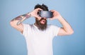 Man with amused look and open mouth enjoying 3D experience. Bearded man with tattoo watching 360 video in VR goggles