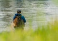 A man or an angler fisherman soaked in water with his fishing rod and net to catch some fish.