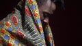 A man from Angola in traditional dashiki clothes puts a bright kerchief on his shoulders, bit slow motion