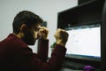 The man is angry clenching his fists in the office in front of computer. Stressful situation during work in pandemic