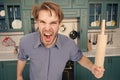 Man with angry face shout with rolling pin in kitchen