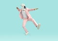 Funny man in horse mask and pink party suit dancing in studio with blue background Royalty Free Stock Photo