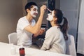 Man applying clay mask on his girlfriend`s face. Young loving couple taking care of skin at home Royalty Free Stock Photo