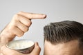 Man applying a clay, pomade, wax, gel or mousse from round metal box for styling his hair after barbershop hair cut Royalty Free Stock Photo