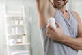 Man applying deodorant in bathroom. Space for text Royalty Free Stock Photo