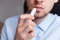 Man applying hygienic lipstick on lips to revive chapped lips and avoid dry, closeup