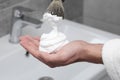 Man applying shaving foam onto brush in bathroom, closeup Royalty Free Stock Photo