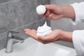 Man applying shaving foam onto brush in bathroom, closeup Royalty Free Stock Photo