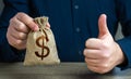 The man approves the deal or loan. Thumbs up and dollar money bag. Royalty Free Stock Photo