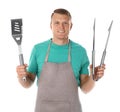 Man in apron with barbecue utensils on white