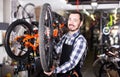 Man in apron considering composition of wheel for bicycle