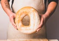 A man in an apron holds fresh bread in his hands with golden crisp. Home bakery baking cooking concept. Royalty Free Stock Photo