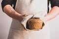 A men in an apron holds various fresh bread loaves with golden crisp in her hands. Homemade alternative bread