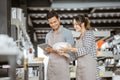 Man in apron using pad with woman while holding plate