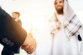 A man in arabian clothes and a man in a business suit are shaking hands. Royalty Free Stock Photo