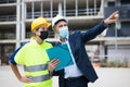 Man architect and a young woman engineer in masks discussing a construction project