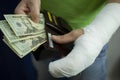 A man with an arm in a cast counted out money from the cost and expenses of emergency medical care at the hospital